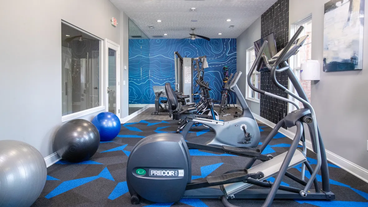 A resident gym featuring modern equipment and a lively ambiance for your workouts. A blue and black carpeted floor instills boldness. While the vibrant blue wall with intriguing lines sparks exploration and creativity.