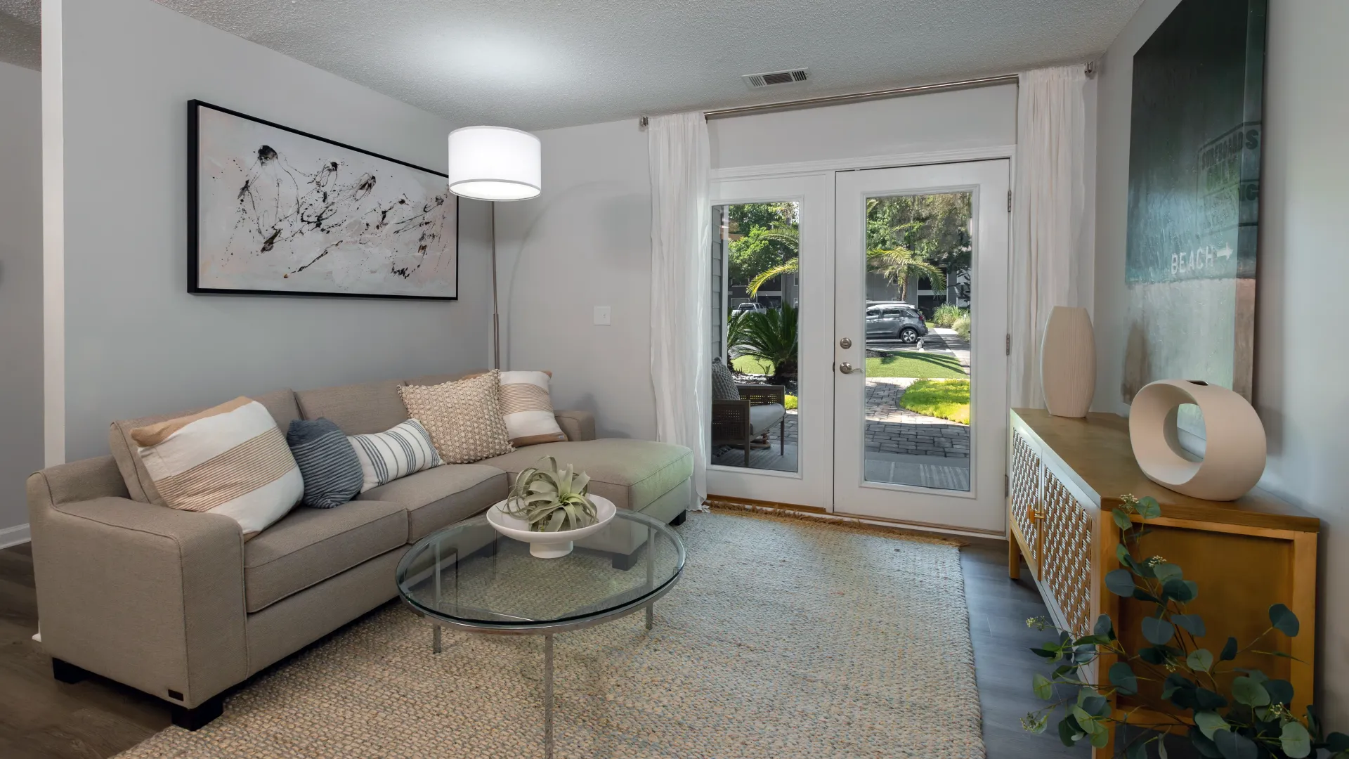 the living room at Emerson Isles, showcasing French doors leading to a private screened-in patio or balcony. 