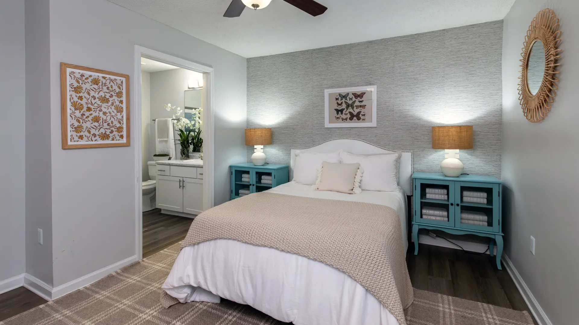 Bedroom at Emerson Isles featuring a bed, a large window bathing the room in natural light, and a ceiling fan. 