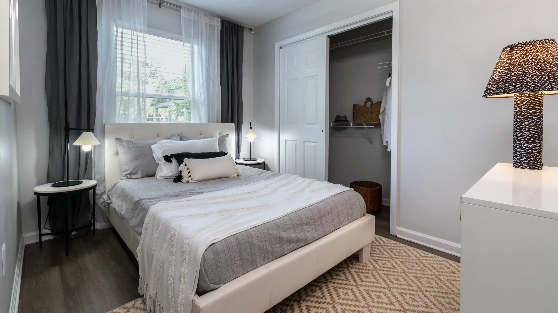 A large bed against a wall with an expansive window, filling the room with natural sunlight