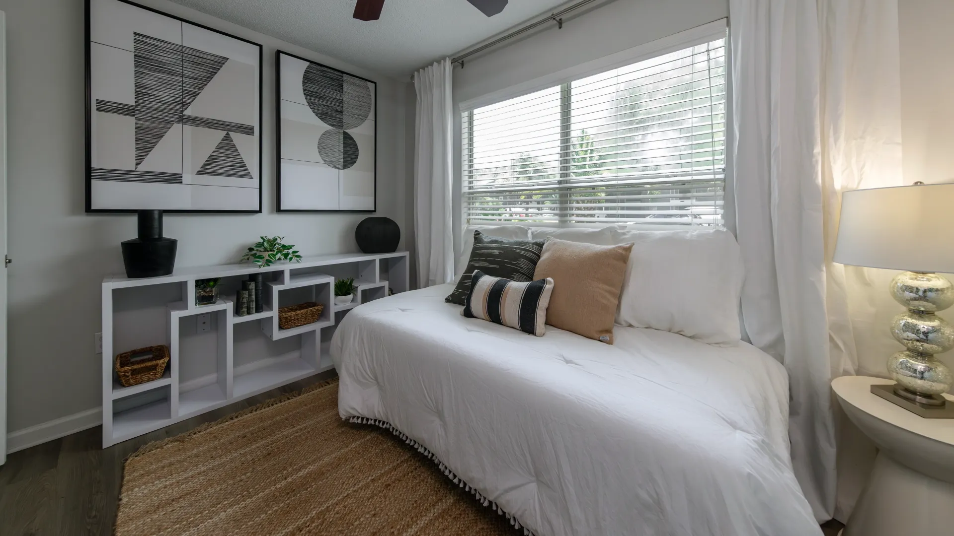 A bedroom with wood-style flooring, large window, and ceiling fan