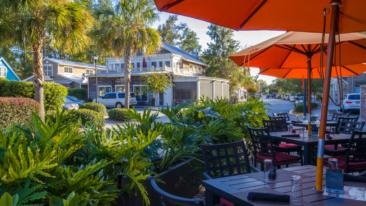 An outdoor patio of a restaurant in downtown Old Town Bluffton, with additional restaurants and shops in the distance.