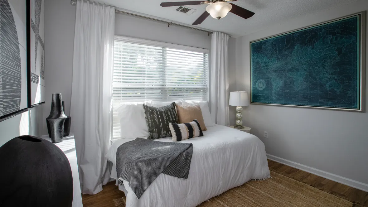 Bedroom at Emerson Isles featuring a bed, a large window bathing the room in natural light, and a ceiling fan.