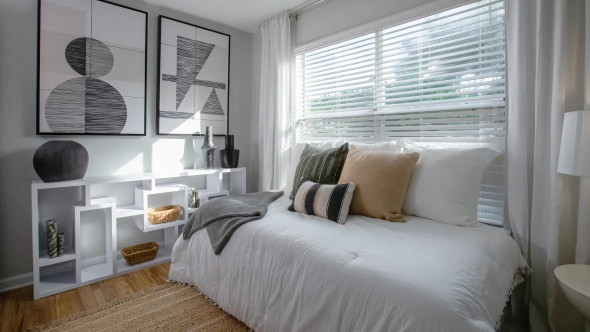 A large bed against a wall with an expansive window, filling the room with natural sunlight.