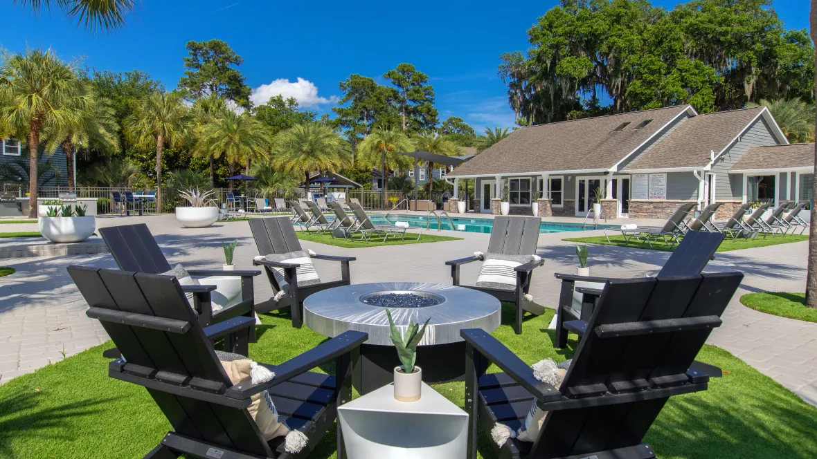 Fire pit surrounded by six Adirondack chairs on the pool deck at Emerson Isles, offering a serene and inviting space for residents to relax and enjoy.