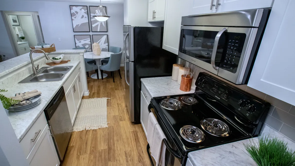 Overhead view of an open galley-style kitchen at Emerson Isles featuring Carrara marble-inspired cabinetry, ample counter space, and a stylish breakfast bar.