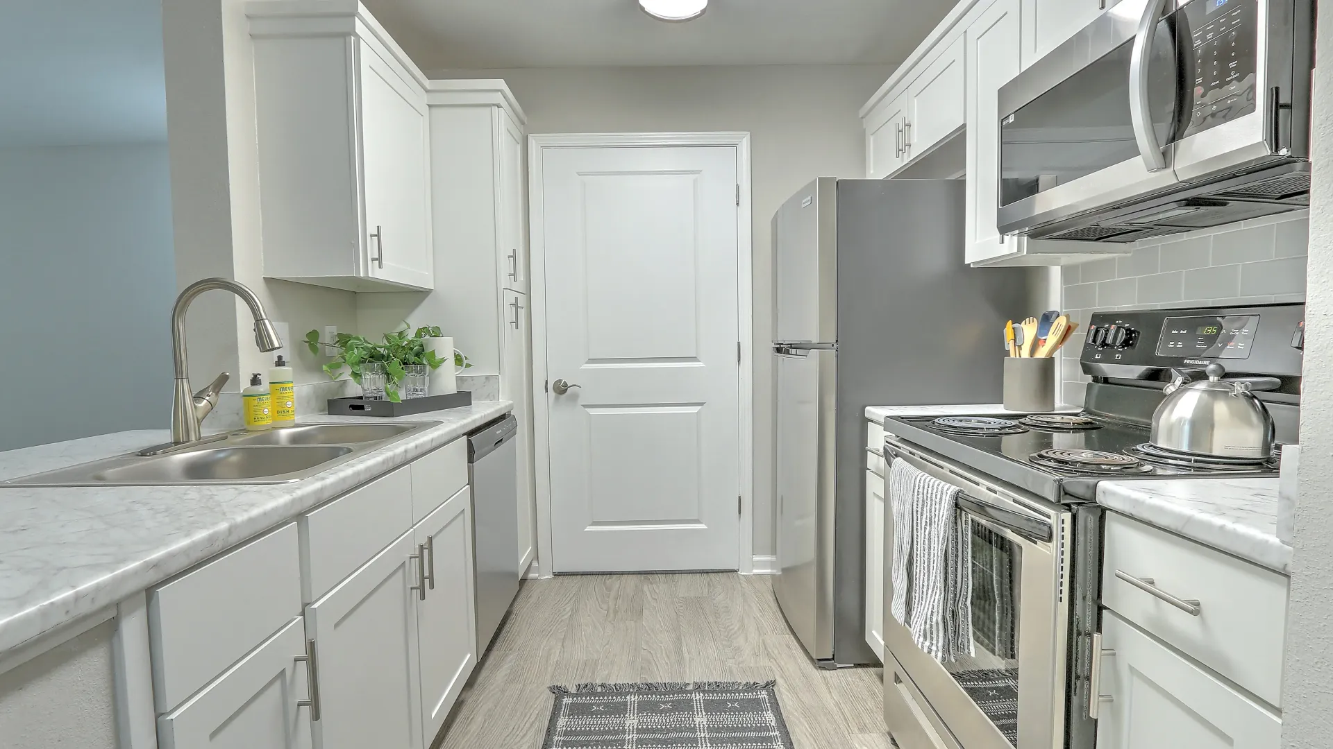 Open kitchen with white cabinetry, stunning white Carrara countertops, stainless steel appliances, and built in pantry.