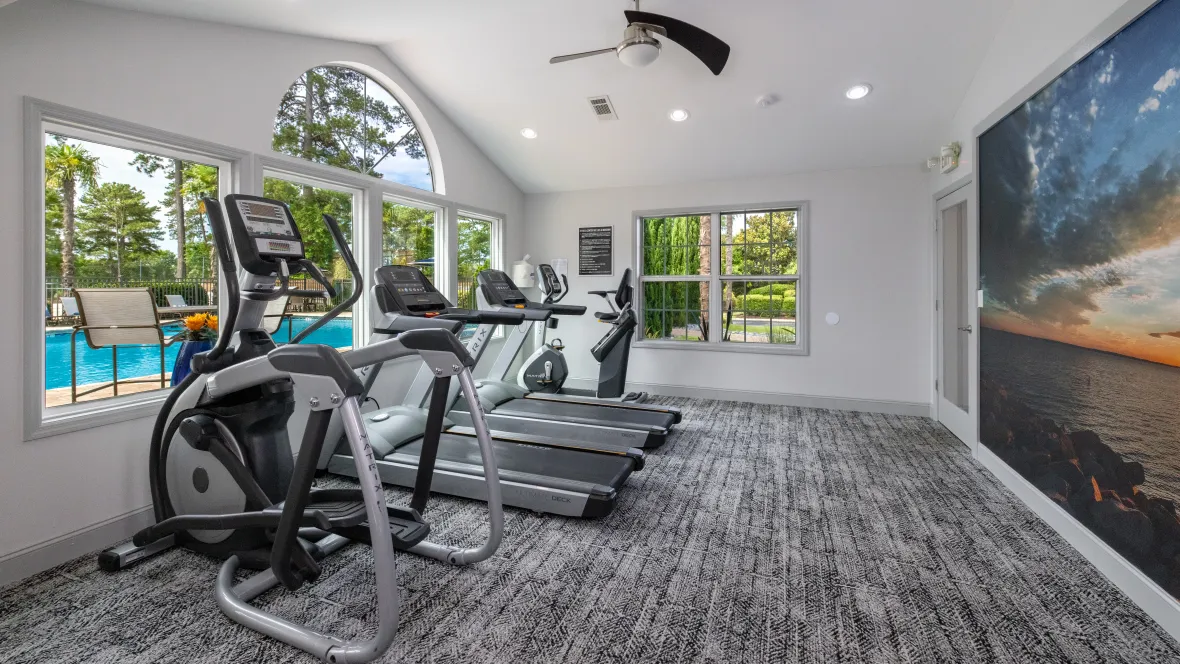 Cardio equipment lined up, including treadmills, ellipticals, and a bike, facing the pool, creating an inspiring workout atmosphere.