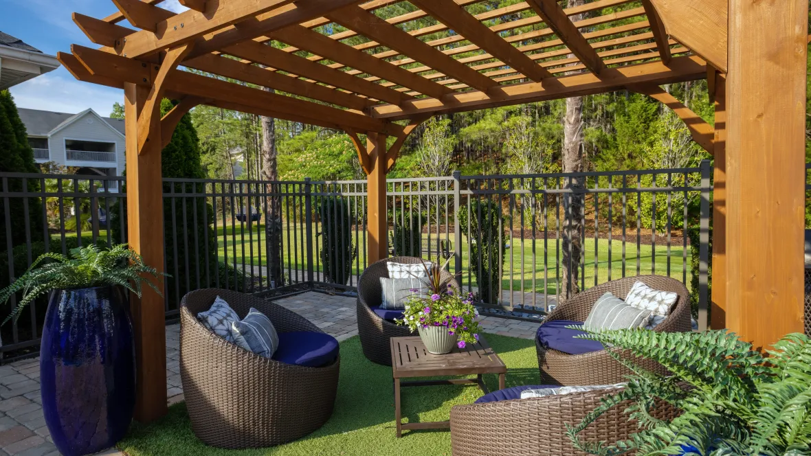 A tranquil oasis under the pergola, offering cozy, cushioned seating and faux grass, creating a premiere ambiance.