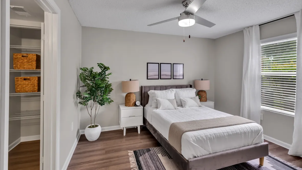 A spacious master bedroom with abundant square footage, large windows, an extra linen closet, and an overhead ceiling fan.