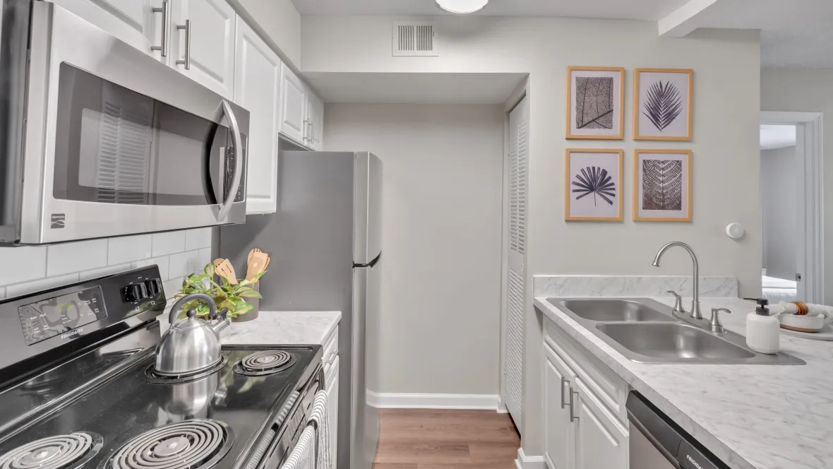 A modern kitchen with pristine white cabinetry and a suite of Frigidaire stainless-steel appliances, including a refrigerator, oven, microwave, and dishwasher.