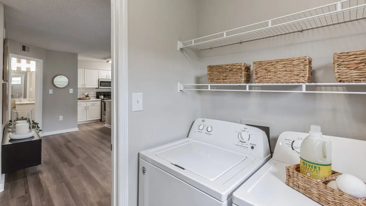 A full-size, side-by-side washer and dryer in a separate laundry room with built-in shelving above for extra storage