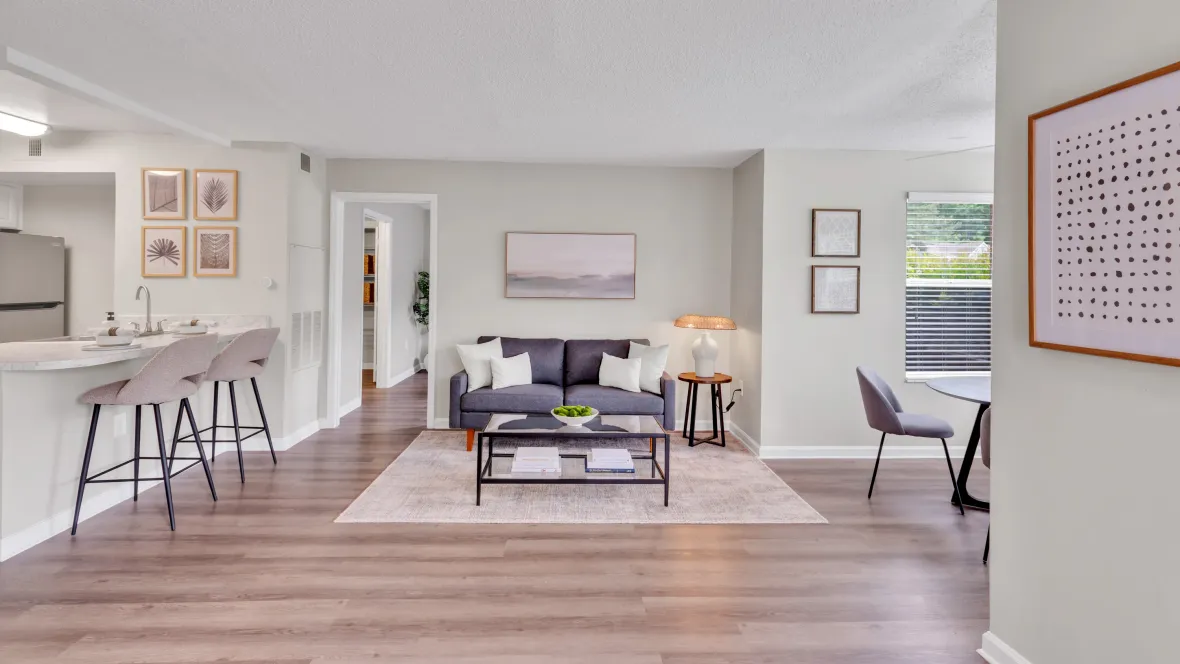 Sunlight floods a spacious living room with sleek wood-like flooring in a neutral palette. The space is open, bright, and ready for enjoyment.