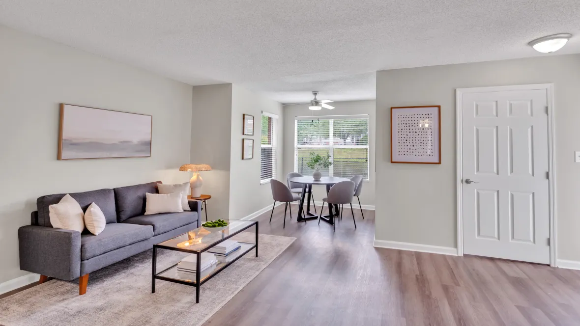 A panoramic view showcases the spacious living and dining area. Abundant natural light fills the elegant dining space with a table, chairs, and a ceiling fan.