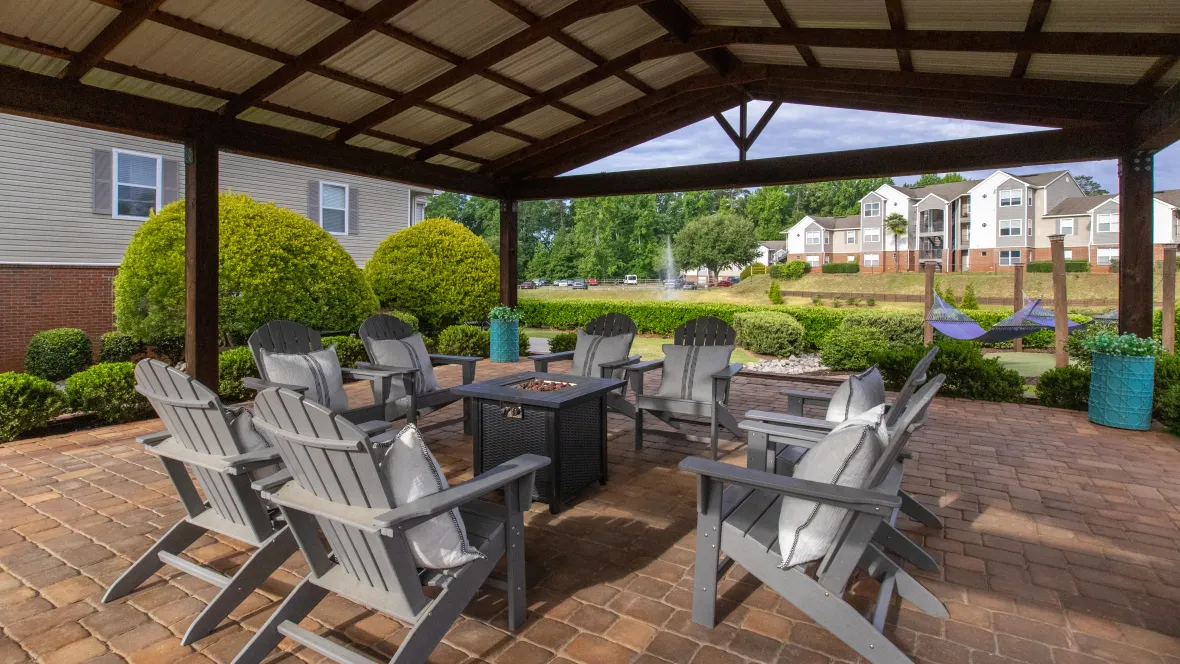 An expansive pavilion with a spacious metal roof, encircled by immaculate landscaping, providing the perfect setting for outdoor gatherings with easy access to the pool and lake, offering prime views.