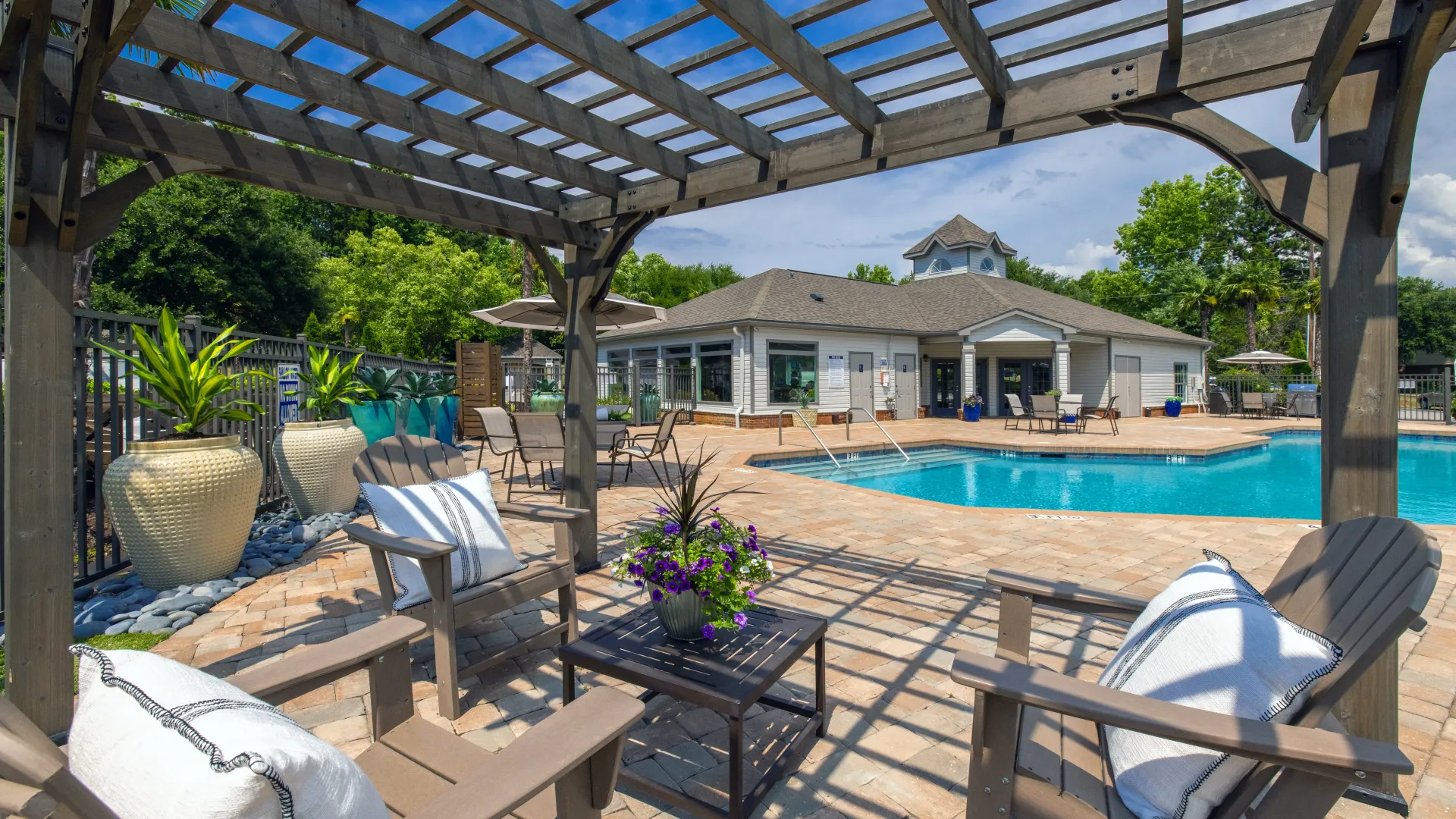 Adirondack seating beneath an elegant pergola offers a prime spot to enjoy the pool and lake's ambiance.